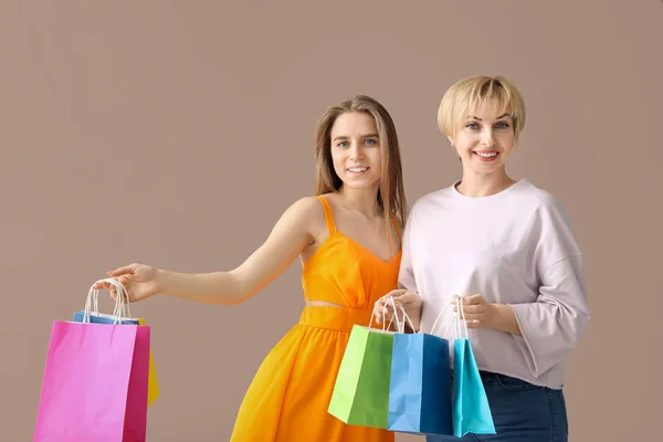 Portrait of mother and daughter with shopping bags on color background — Stock Photo, Image