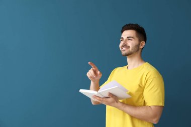 Renk arka plan üzerinde kitapla yakışıklı genç