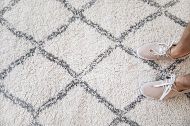 Yumuşak halı üzerinde duran adamın bacakları, üst görünümü