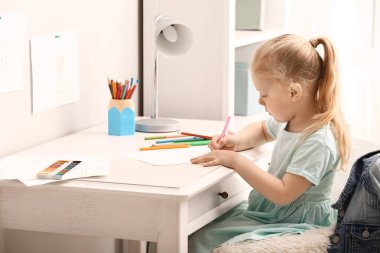 Küçük kız evde çizim yapıyor.