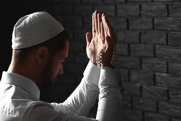 어두운 벽돌 벽에 대해기도 하는 젊은 무슬림 남자 — 스톡 사진