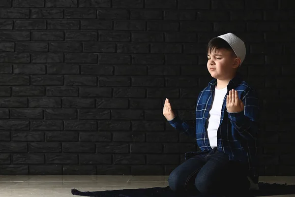 Little Muslim boy praying against dark wall — Stock Photo, Image