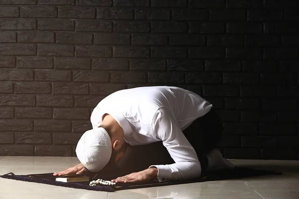 Jovem muçulmano rezando contra a parede de tijolos escuros — Fotografia de Stock