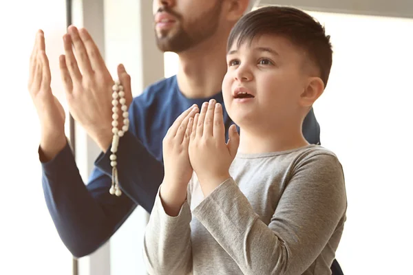 Young Muslim man and his son praying indoors — Stock Photo, Image