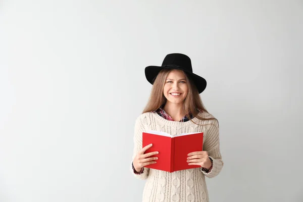 Bella giovane donna con libro su sfondo chiaro — Foto Stock