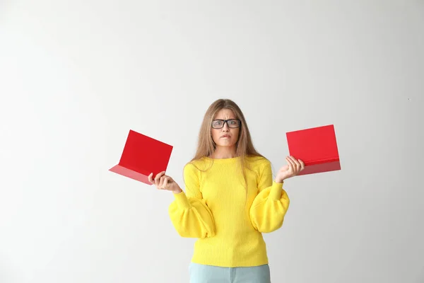 Confuso giovane donna con libri su sfondo chiaro — Foto Stock