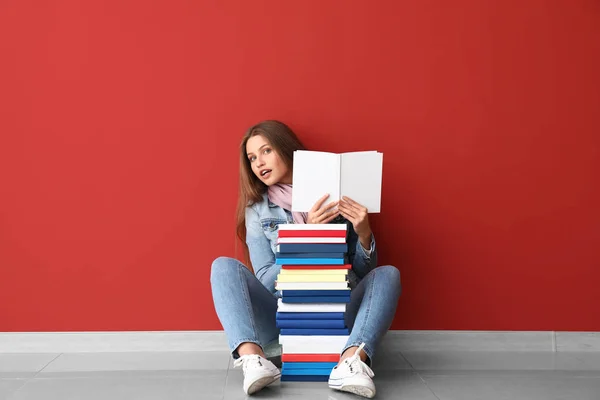 Красива молода жінка з книгами біля кольорової стіни — стокове фото