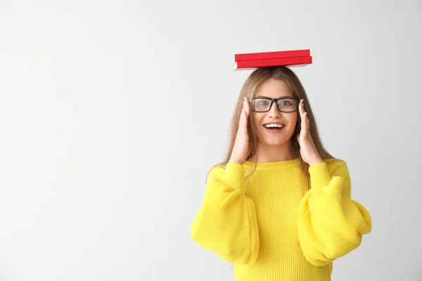 Happy young woman with books on light background — Stock Photo, Image