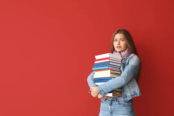 Stressato giovane donna con libri su sfondo a colori — Foto Stock
