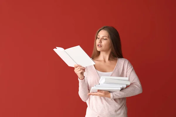 Schöne junge Frau mit Büchern auf farbigem Hintergrund — Stockfoto