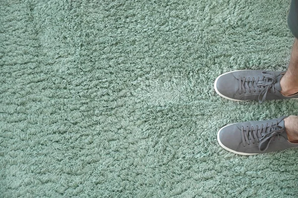 Nogi człowieka stojące na miękkim dywanie, widok z góry — Zdjęcie stockowe