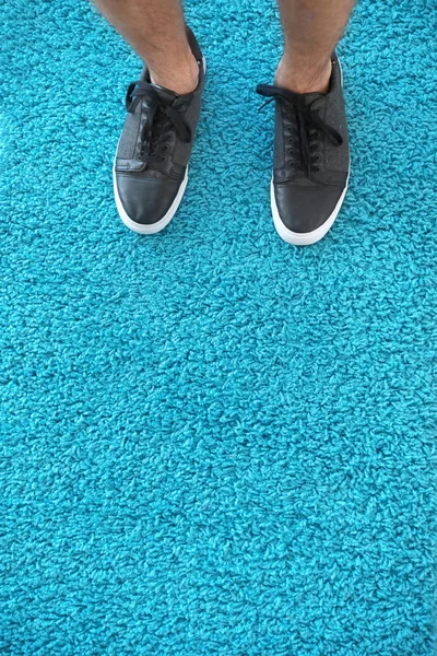 Legs of man standing on soft carpet, top view — Stock Photo, Image