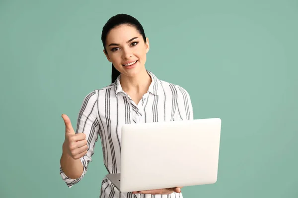 Programmiererin mit Laptop zeigt Daumen-hoch-Geste auf farbigem Hintergrund — Stockfoto