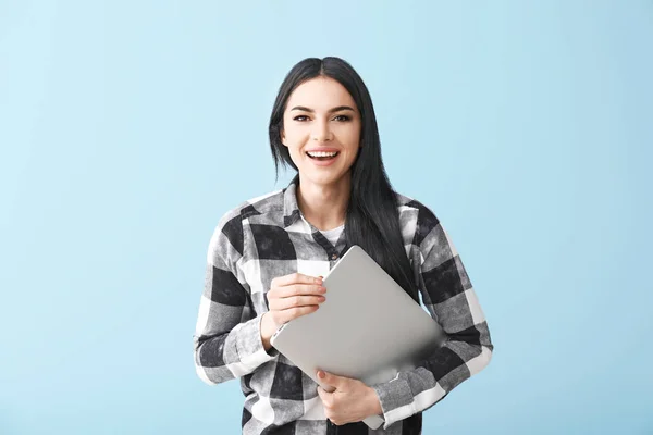 Glückliche Programmiererin mit Laptop auf farbigem Hintergrund — Stockfoto