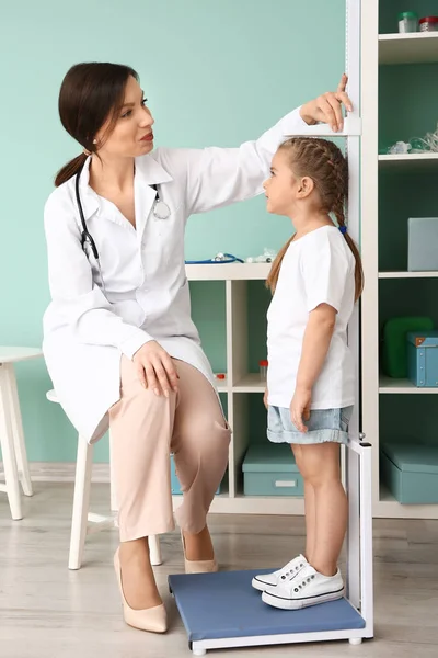 Médico femenino midiendo la altura de una niña en el hospital — Foto de Stock