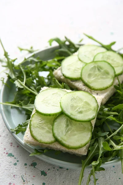 Plate with tasty cucumber sandwiches on light table