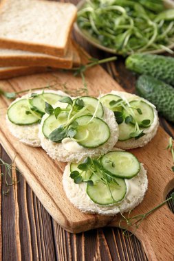 Ahşap masa üzerinde lezzetli salatalık sandviç ile Kurulu