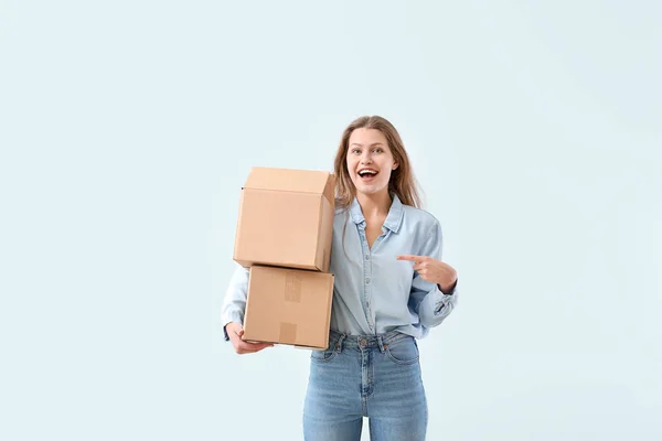 Young woman with cardboard boxes on light background — Stock Photo, Image