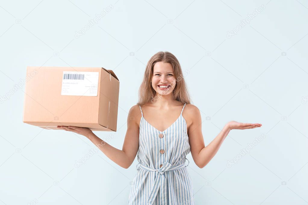 Happy woman with cardboard box on light background