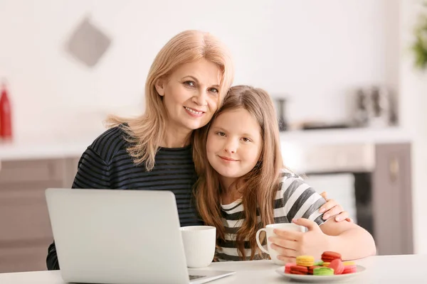 Ώριμη γυναίκα και την χαριτωμένη εγγονή της με το laptop πόσιμο τσάι στο σπίτι — Φωτογραφία Αρχείου
