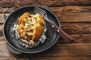Ahşap masada lezzetli doldurulmuş patates ile kızartma tavası