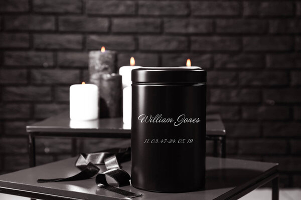 Mortuary urn with ribbon on table in room