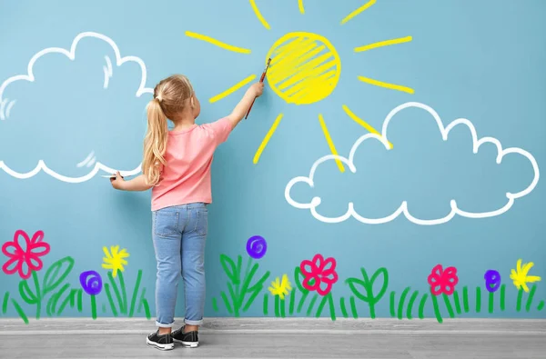 Kleines Mädchen malt Sonne, Blumen und Wolken auf Farbwand — Stockfoto