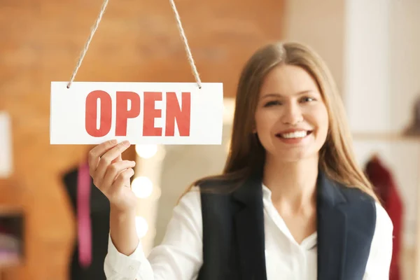 Beautiful female business owner near opening sign in atelier — Stock Photo, Image
