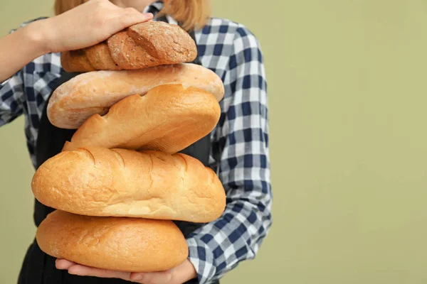 Female baker with bread on color background, closeup — Stock Photo, Image