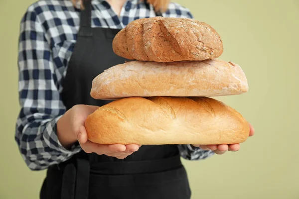 Female baker with bread on color background, closeup — Stock Photo, Image