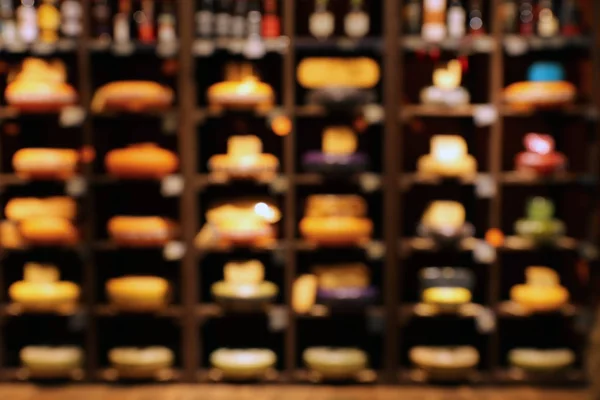 Wheels of delicious cheese in shop, blurred view