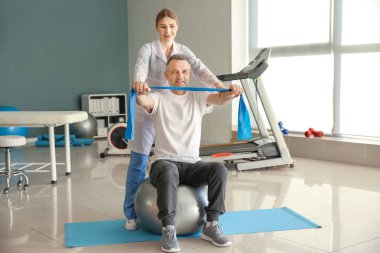 Rehabilitasyon merkezinde olgun hasta ile çalışan fizyoterapist