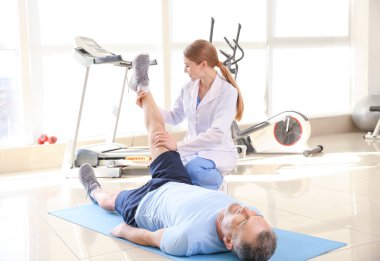 Rehabilitasyon merkezinde olgun hasta ile çalışan fizyoterapist