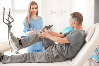 Rehabilitasyon merkezinde olgun hasta ile çalışan fizyoterapist