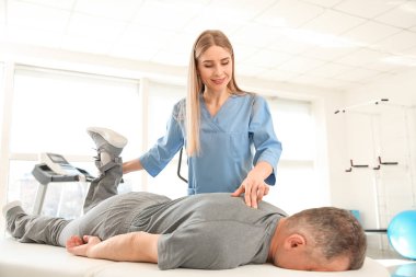 Rehabilitasyon merkezinde olgun hasta ile çalışan fizyoterapist