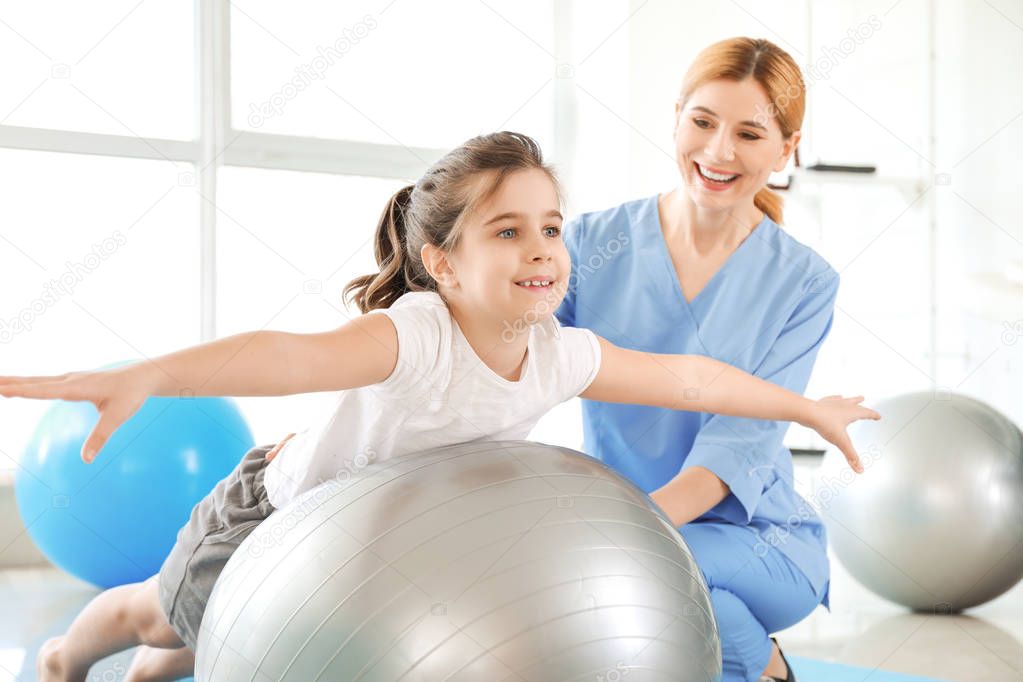 Physiotherapist working with little girl in rehabilitation center