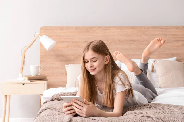 Cute teenage girl with tablet computer in bedroom at home — Stock Photo, Image