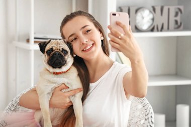 Genç kız evde sevimli pug köpek ile selfie alarak