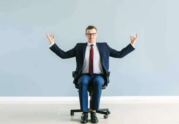 Businessman meditating while sitting on chair indoors — Stock Photo, Image