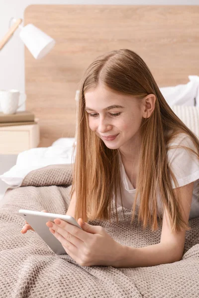 Cute teenage girl with tablet computer in bedroom at home — Stock Photo, Image