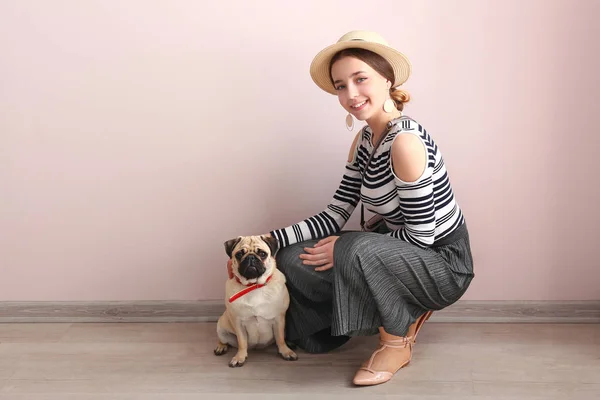 Девочка-подросток с милой собакой-мопсом возле цветной стены — стоковое фото