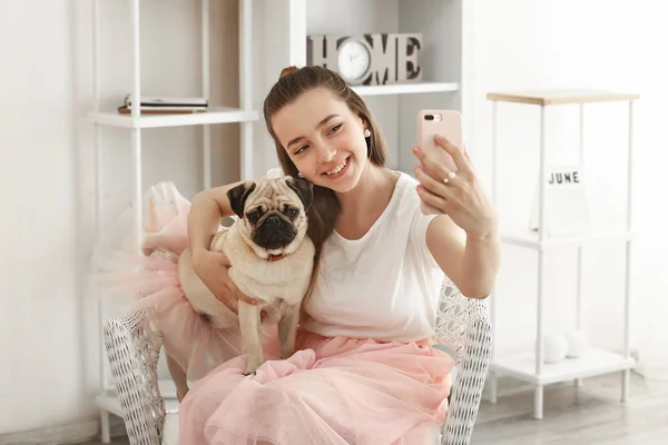 Ragazza adolescente che prende selfie con simpatico cane carlino a casa — Foto Stock
