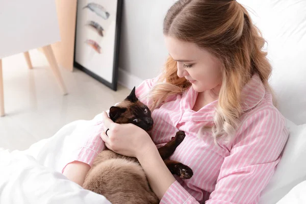 Junge Frau mit süßer thailändischer Katze im Schlafzimmer — Stockfoto