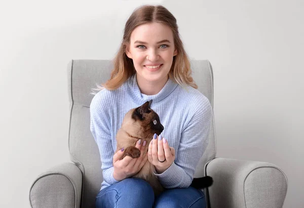 Mujer joven con lindo gato tailandés sentado en sillón — Foto de Stock