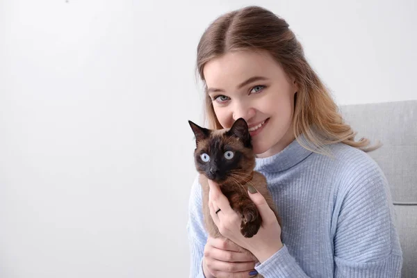 Mujer joven con lindo gato tailandés sentado en sillón — Foto de Stock