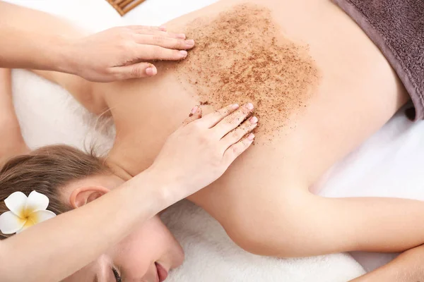 Young woman undergoing treatment with body scrub in spa salon — Stock Photo, Image