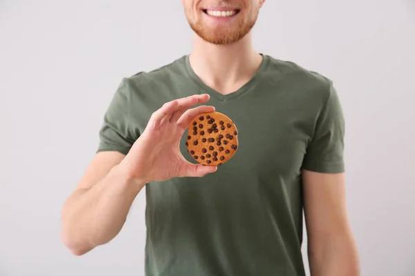 Красивий молодий чоловік зі смачним печивом на світлому фоні — стокове фото