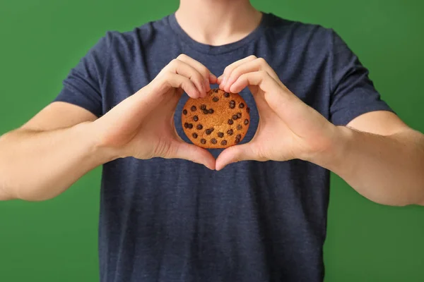Красивий молодий чоловік зі смачним печивом на кольоровому фоні, крупним планом — стокове фото