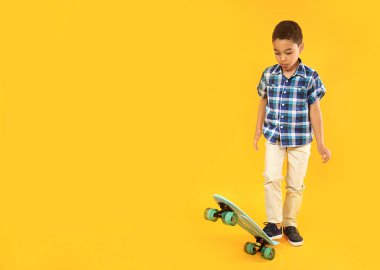 Renkli arka planda kaykay ile sevimli küçük çocuk Portresi