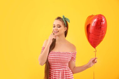 Renk arka planda kalp şeklinde hava balonu ile güzel genç kadın